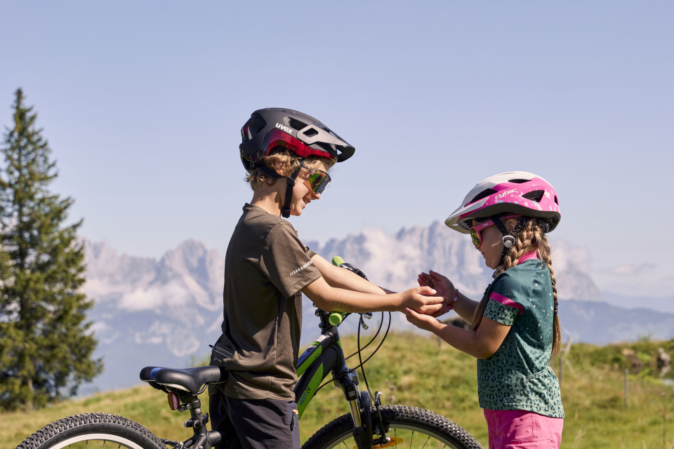 Two children in cycling gear clap their hands