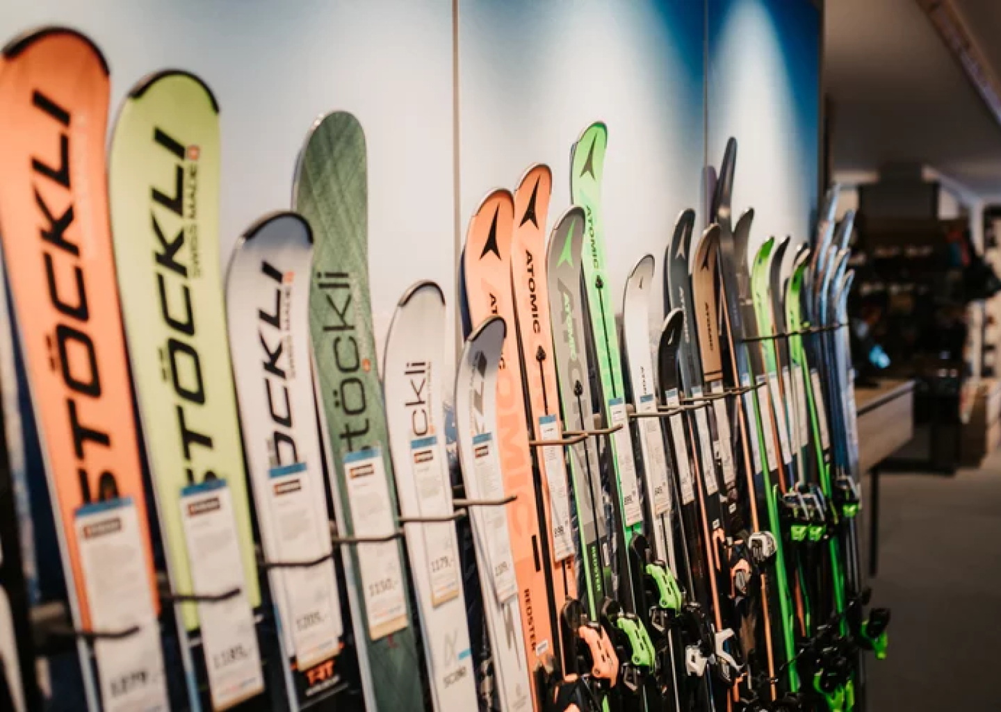 Skisportgeschäft-Auslage: Reihe von Stöckli- und Atomic-Skiern zum Verkauf, die Wintersportausrüstung präsentieren.